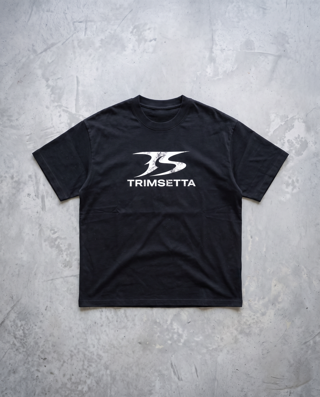 Blackout Tee – flat lay on concrete